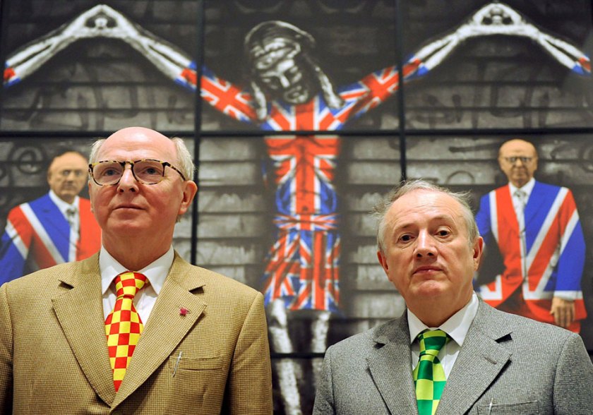 Artist duo George (left) and Gilbert (right) pose in front of their work "The Church of England" in Berlin, Germany