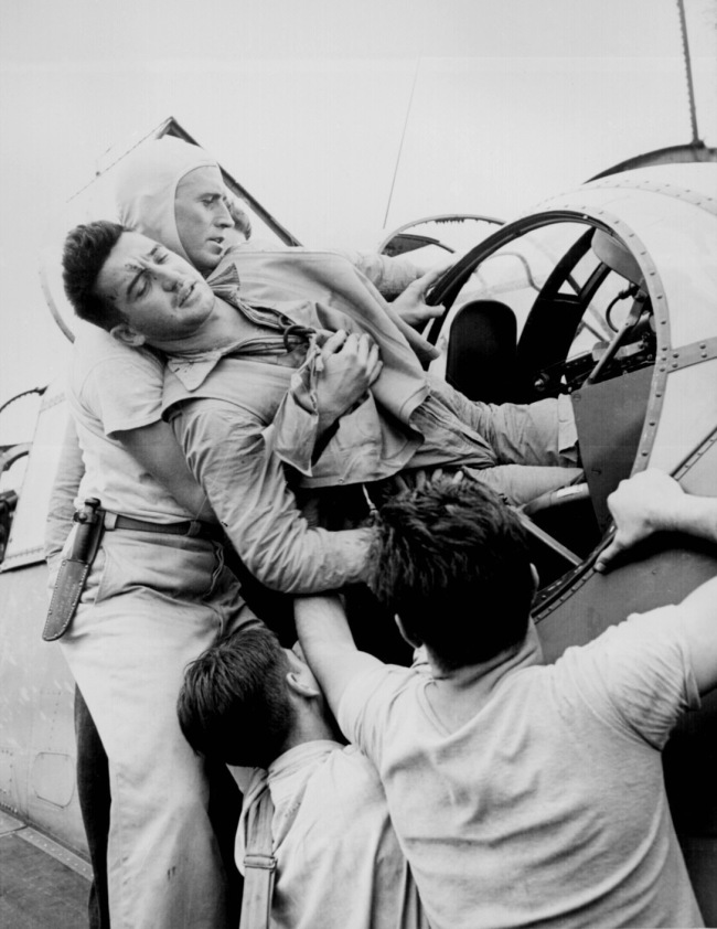 Lt. Wayne Miller. 'Crewmen lifting Kenneth Bratton out of turret of TBF on the USS SARATOGA after raid on Rabaul' November 1943