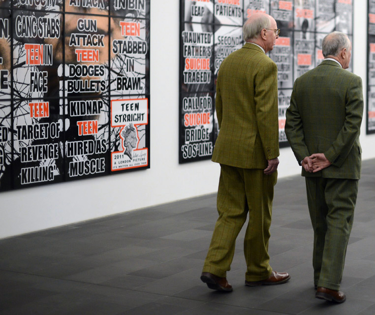 The British artists George Passmore (L) and Gilbert Prousch (R) pass in front of one of their art work 'London Pictures'