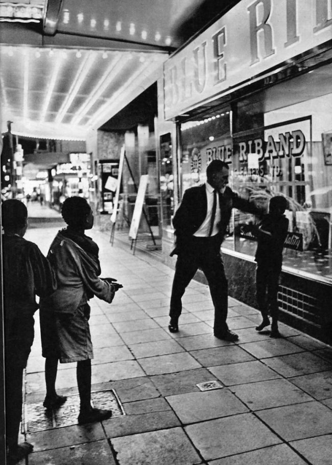 Ernest Cole (South African, 1940-1990) '"Penny, baas, please baas, I hungry…" This plaint is part of nightly scene in Golden City, as black boys beg from whites. They may be thrown a coin or, as here, they may get slapped in the face' 1960-1966