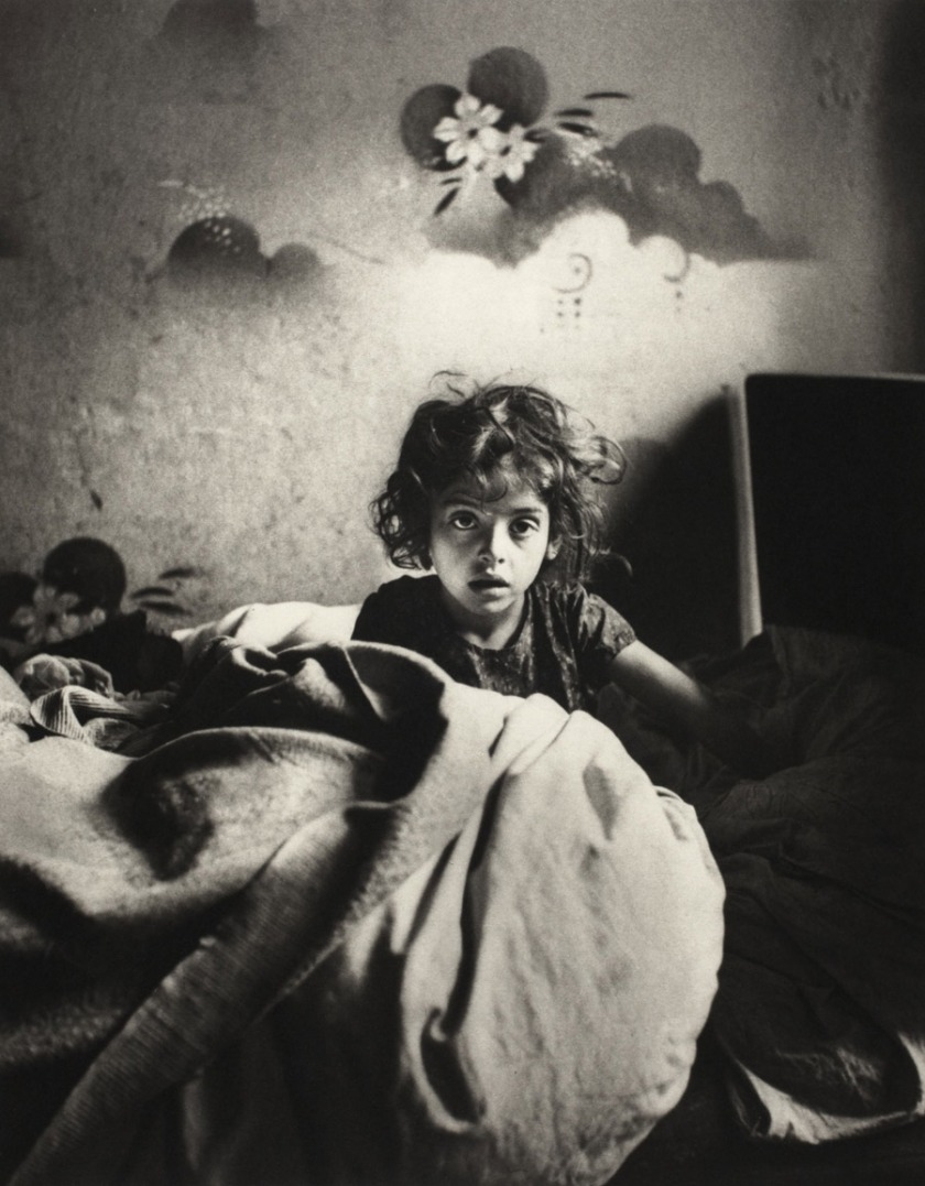 Roman Vishniac. '[Sara, sitting in bed in a basement dwelling, with stenciled flowers above her head, Warsaw]' c. 1935-37