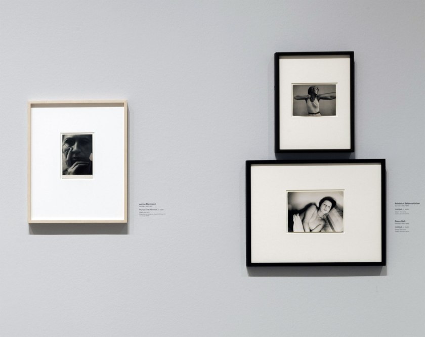 Installation view of the exhibition 'New Objectivity: Modern German Art in the Weimar Republic, 1919-1933' at LACMA showing Aenne Biermann, 'Woman with Monocle' (Dame mit Monokel), c. 1928 at left, with photographs by Friedrich Seidenstücker (right top) and Franz Roh (right bottom)
