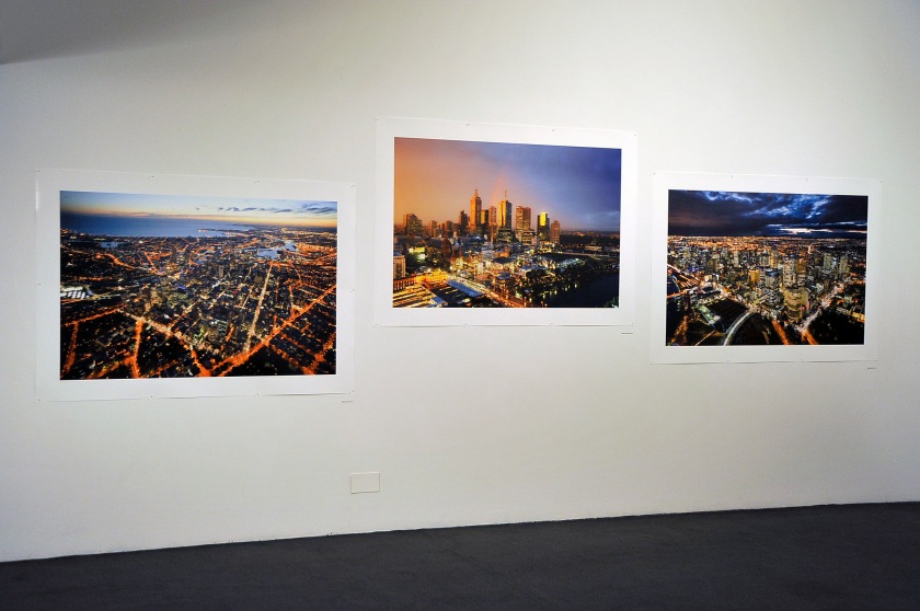 Installation view of the exhibition 'John Gollings: The history of the built world' at the Monash Gallery of Art showing at left, 'Melbourne CBD, Melbourne, Victoria' 2009; middle, 'Federation Square, Melbourne, Victoria' 2010; and right, 'Melbourne CBD, Melbourne, Victoria' 2010