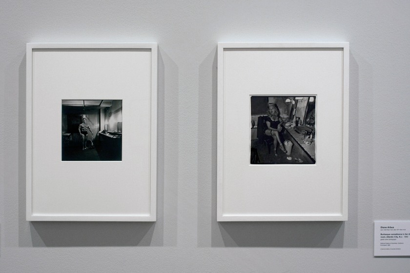 Installation view of the exhibition 'Diane Arbus: American Portraits' at the Heide Museum of Modern Art, Melbourne showing at left, Diane Arbus' 'Muscle Man in his dressing room with trophy, Brooklyn, N.Y.' 1962 and at right, 'Burlesque comedienne in her dressing room, Atlantic City, N.J.' 1963
