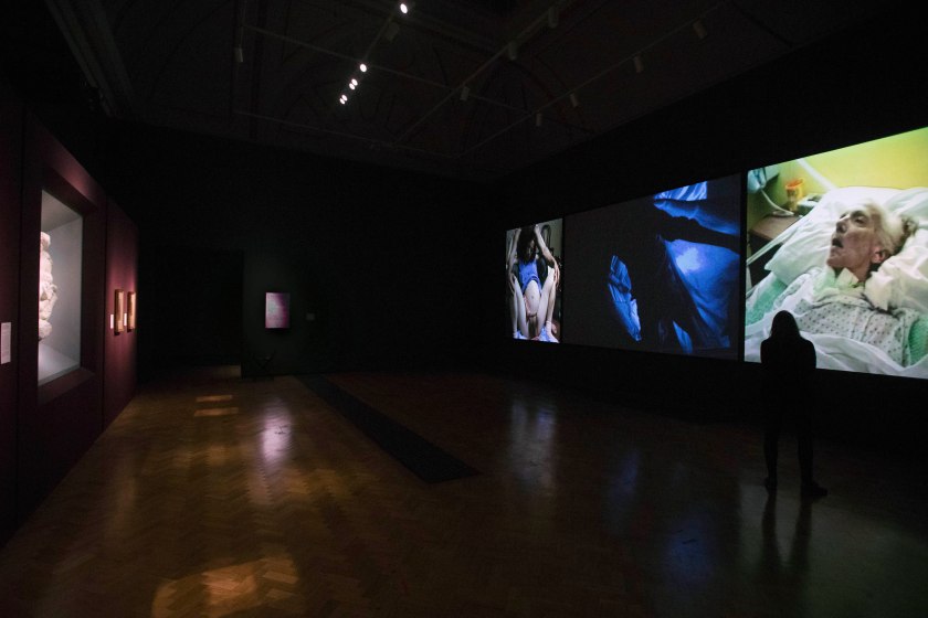 Installation view of the exhibition 'Bill Viola/Michelangelo: Life, Death, Rebirth' at the Royal Academy of Arts, London with at left Michelangelo's 'The Virgin and Child with the Infant St John (Taddei Tondo)' c. 1504-1505; and at right, Bill Viola's 'Nantes Triptych', 1992