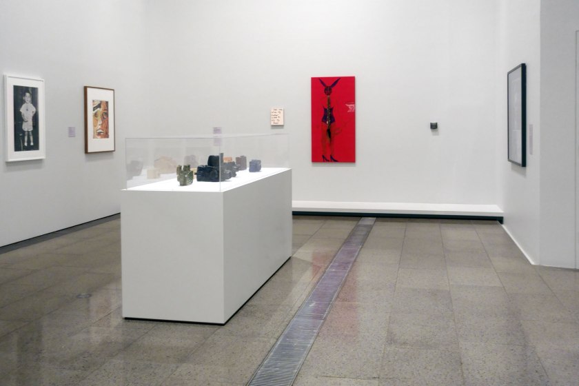 Installation view of the exhibition 'WHO ARE YOU: Australian Portraiture' at NGV Australia, Federation Square, Melbourne showing at left, William Yang's 'Self Portrait #2' (2007); and at centre in case, Alan Constable's earthenware cameras