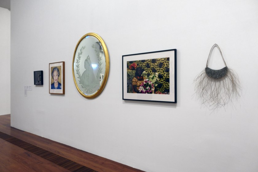 Installation view of the exhibition 'WHO ARE YOU: Australian Portraiture' at NGV Australia, Federation Square, Melbourne showing at second left, Polly Borland's 'HM Queen Elizabeth II' (2002); at second right, Atong Atem's 'Adut' (2015); and at right, Treahna Hamm's 'Barmah Forest breastplate' (2005)