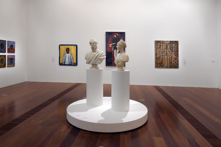 Installation view of the exhibition 'WHO ARE YOU: Australian Portraiture' at NGV Australia, Federation Square, Melbourne showing at second left background, AñA Wojak's 'Acacius (Stigmata) – Tony Carden' (1991); at centre background, Julie Rrap's 'Persona and shadow: Madonna' (1984); and at centre on pedestal, Charles Summers' 'Edmund FitzGibbon and Sarah FitzGibbon' (1877)