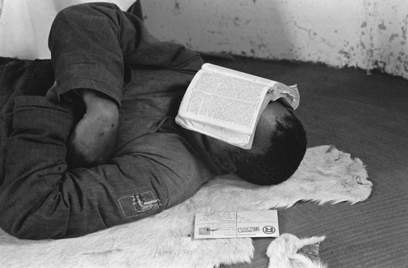 Ernest Cole (South African, 1940-1990) 'Piet falls asleep with Bible on his face, Africans say: "When the Europeans came, they had the Bible. Now we have the Bible, and they have our land".' 1960-1966