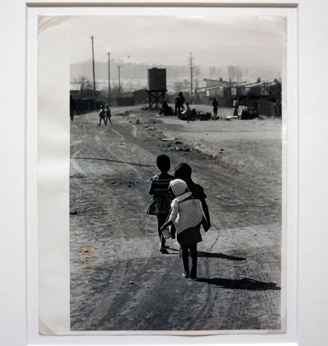 Ernest Cole (South African, 1940-1990) 'With older children in school and mothers at work, baby bay-minders are common sight on African township streets' 1960-1966 (installation view)