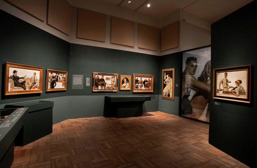 Installation view of the exhibition 'Under Cover: J.C. Leyendecker and American Masculinity' at the New-York Historical Society showing at second left, 'In the Stands 2' (1913); at centre, 'Portrait of an American Sailor, Charles Beach' (1918); at third right, 'Man and Woman with Spanish Shawl' (1926); and at right, 'Couple in Boat' (1912)