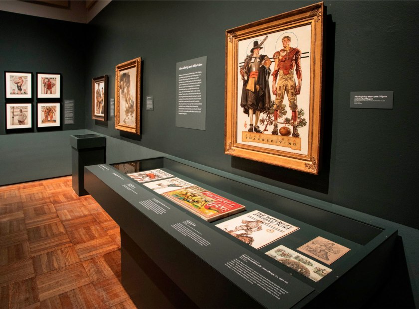 Installation view of the exhibition 'Under Cover: J.C. Leyendecker and American Masculinity' at the New-York Historical Society showing at left in the bottom image, 'Cover of Saturday Evening Post' (June 29, 1907) and 'Cover of Collier's' (June 24, 1916); at second right, 'In the Yale Boathouse' (1905); and at right, 'Thanksgiving: 1628-1928 (Pilgrim and Football Player)' (1928)