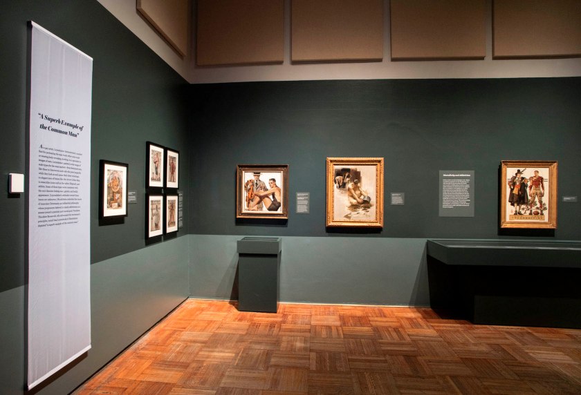 Installation view of the exhibition 'Under Cover: J.C. Leyendecker and American Masculinity' at the New-York Historical Society showing at left centre, 'Record Time, Cool Summer Comfort' (c. 1920); at centre, 'In the Yale Boathouse' (1905); and at right, 'Thanksgiving: 1628-1928 (Pilgrim and Football Player)' (1928)