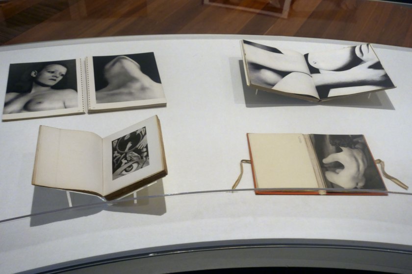 Installation view of the exhibition 'Photography: Real & Imagined' at The Ian Potter Centre: NGV Australia, Melbourne showing at top left, Man Ray's book 'Photographs by Man Ray Paris 1920-1934' (published 1934); at bottom left, Claude Cahun and Marcel Moore's book 'Aveux non Avenus' (Disavowals or Cancelled Confessions) (published 1930); at top right, Bill Brandt's book 'Perspective of Nudes' (published 1961); and at bottom right, Germaine Krull's book 'Nude studies' (Études de nu) (published 1930)