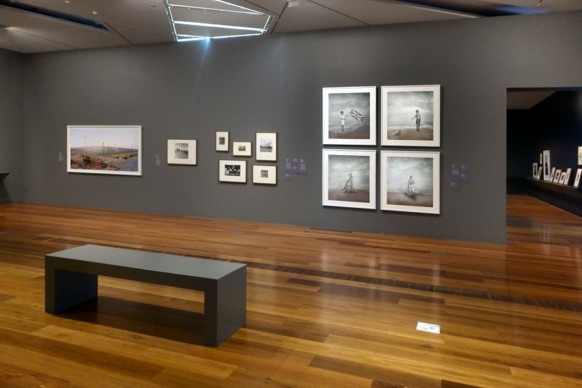 Installation view of the exhibition 'Photography: Real & Imagined' at The Ian Potter Centre: NGV Australia, Melbourne showing at left, Rosemary Laing's 'welcome to Australia' (2004, above); and at right, four photographs from Michael Cook's 'Civilised' series (2012)