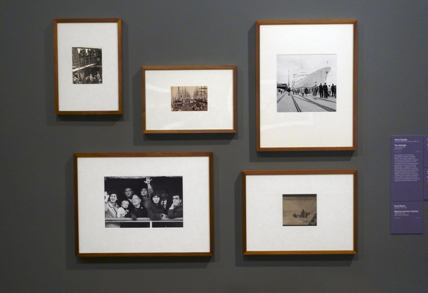 Installation view of the exhibition 'Photography: Real & Imagined' at The Ian Potter Centre: NGV Australia, Melbourne showing at top left, Alfred Stiegliz's 'The steerage' (1907); at bottom left, David Moore's 'Migrants arriving in Sydney' (1966); at centre, Charles Nettleton's 'Hobsons Bay railway pier' (1870s); at top right, Maggie Diaz's 'The Canberra, Port Melbourne' (1961-1967); and at bottom right, Paul Haviland's 'Passing steamer' (1910)